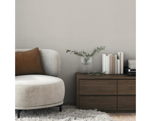 Wohnzimmer mit Sessel, Kissen, Kommode, Büchern und Vase