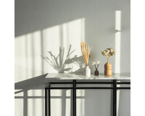 Dekorative Trockenblumen in Vasen auf einem Tisch vor einer gemusterten Wand