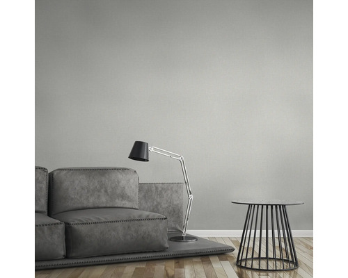 Salon avec canapé gris, lampadaire et table d''appoint devant un revêtement mural.