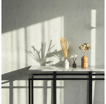 Wand mit Muster, Tisch mit Dekoration wie Vasen und Trockenblumen.