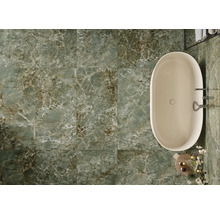 Salle de bains avec baignoire et carrelage de sol vert aspect marbre.