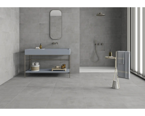 Salle de bain lumineuse avec carrelage gris, lavabo avec miroir et douche