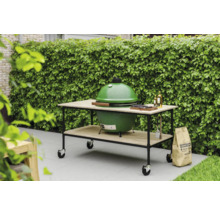 Barbecue vert sur une table à roulettes, sac de charbon de bois dans le jardin.