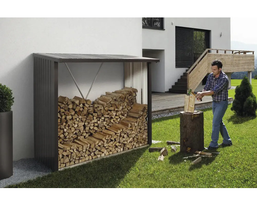 Étagère à bois de chauffage en métal avec bois et homme coupant du bois dans le jardin