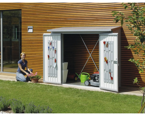 Gartenschrank mit geöffneten Türen, ausgestattet mit Gartengeräten, Rasenmäher und Giesskanne im Garten.
