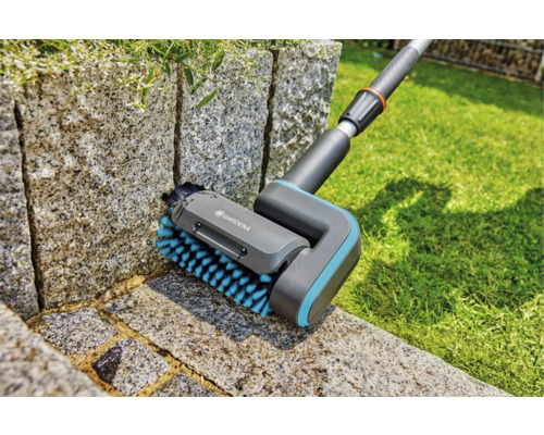 Brosse Gardena pour le nettoyage des joints en utilisation sur un mur de pierre