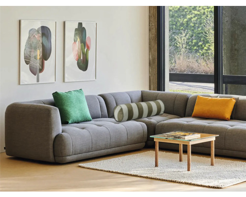 Wohnzimmer mit grauer Eckcouch, Kissen, Couchtisch und Wandbildern