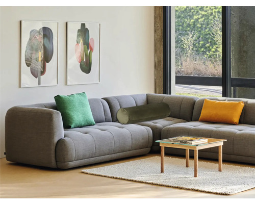 Wohnzimmer mit grauer Eckcouch, Kissen und kleinem Tisch