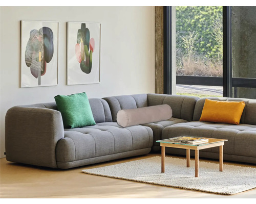 Graues Ecksofa mit Kissen und kleinem Tisch im Wohnzimmer.