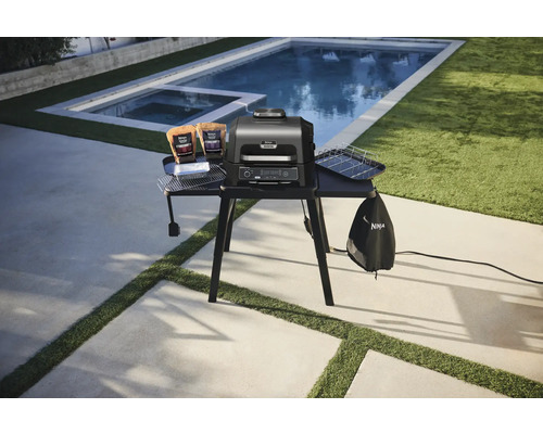 Gril électrique Ninja Woodfire avec accessoires sur une table à l''extérieur