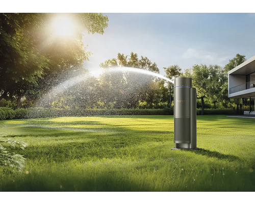 Arroseur arrosant un jardin devant une maison moderne.