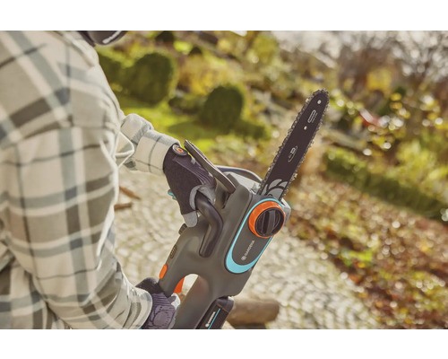 Une personne utilise une tronçonneuse à batterie Gardena dans le jardin.