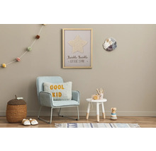 Dekoriertes Kinderzimmer mit Sessel, Beistelltisch, Spielzeug und Wanddekorationen.