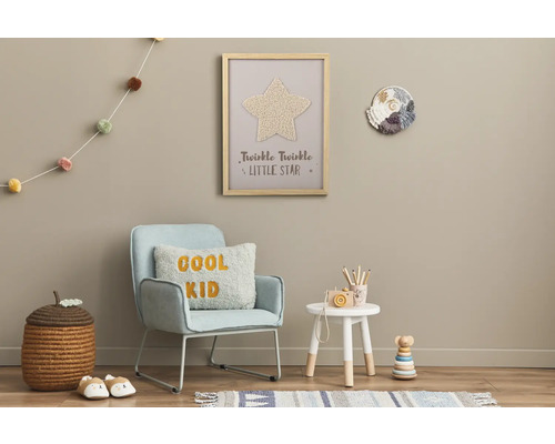 Dekoriertes Kinderzimmer mit Sessel, Beistelltisch, Spielzeug und Wanddekorationen.