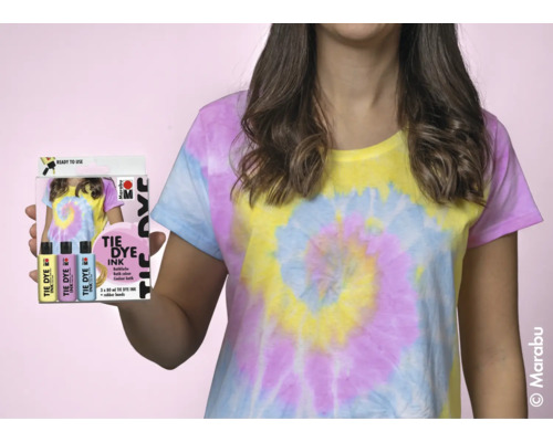 Femme avec T-shirt batik tient un paquet de teinture batik Marabu à la main