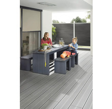 Famille assise à une table de jardin avec des bancs sur une terrasse avec plancher en bois