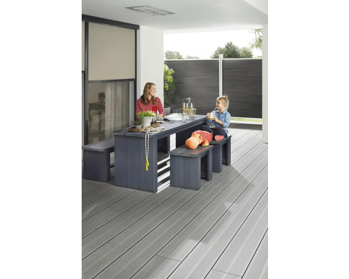Famille assise à une table de jardin avec des bancs sur une terrasse avec plancher en bois