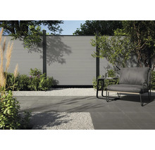 Scène de jardin avec dalle de terrasse grise, gravier et siège devant une clôture.