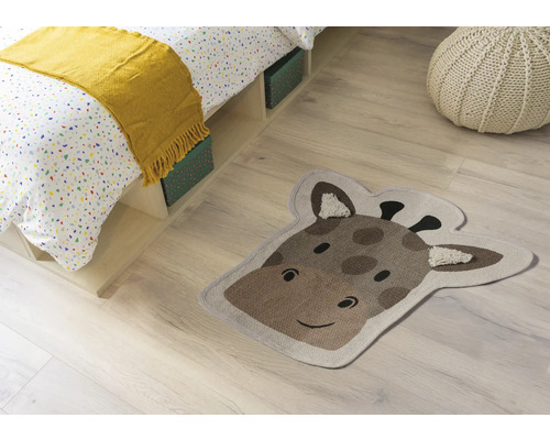 Zimmerszene mit Bett, Sitzkissen und einem Teppich in Form eines Giraffenkopfes.