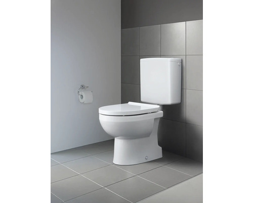 Toilette blanche avec réservoir apparent devant un carreau mural gris et un porte-papier hygiénique