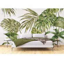 Chambre avec un ensemble de literie blanc devant un papier peint à feuilles tropicales