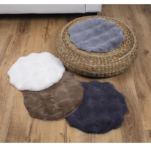 Szene mit einem runden Strohhocker und mehreren Plüschkissen in verschiedenen Formen