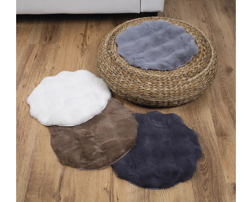 Szene mit einem runden Strohhocker und mehreren Plüschkissen in verschiedenen Formen