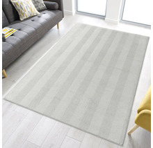 Rechteckiger Teppich mit Fischgrätenmuster in einem hellen Wohnraum.