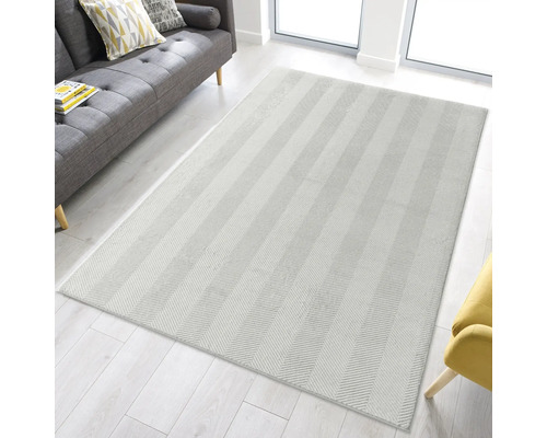 Rechteckiger Teppich mit Fischgrätenmuster in einem hellen Wohnraum.