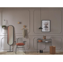 Wohnraum mit Spiegel, Stuhl, Regal und dekorativen Elementen vor einer Wand mit Zierleisten