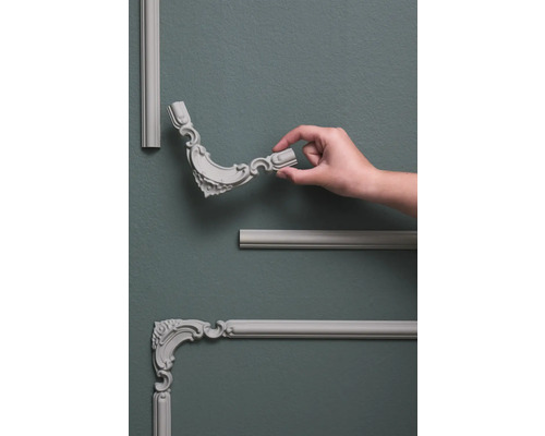 Wandpaneele mit Zierelementen und Hand auf grauer Wand