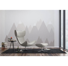 Salon moderne avec fauteuil, tabouret, table d'appoint et papier peint motif montagne.