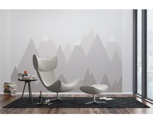 Salon moderne avec fauteuil, tabouret, table d'appoint et papier peint motif montagne.