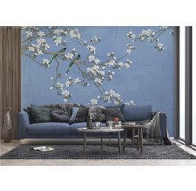 Salon avec un canapé bleu devant un papier peint à motif d'oiseaux et de fleurs