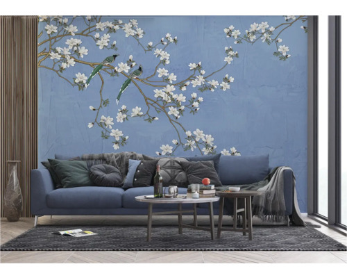 Salon avec un canapé bleu devant un papier peint à motif d'oiseaux et de fleurs