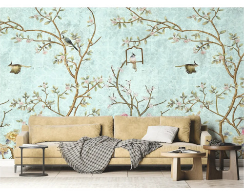 Salon avec papier peint à motifs d'oiseaux et de fleurs, canapé et tables d'appoint.