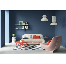 Salon avec canapé, fauteuil, tapis et étagères sur un mur coloré