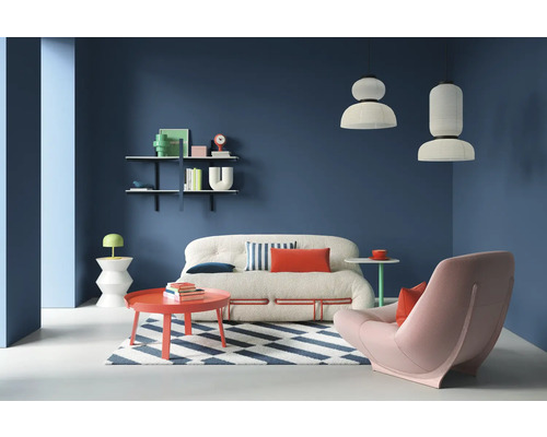 Salon avec canapé, fauteuil, tapis et étagères sur un mur coloré