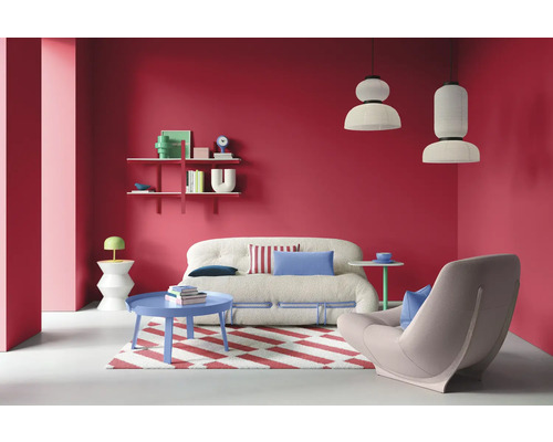 Salon avec canapé, fauteuil, tapis, table et étagères devant un mur rouge
