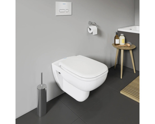 WC suspendu avec brosse de toilette, plaque de commande, porte-papier toilette et table d'appoint dans la salle de bains.