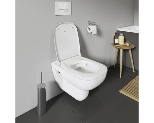 WC suspendu avec brosse de toilette et plaque de commande dans la salle de bain.