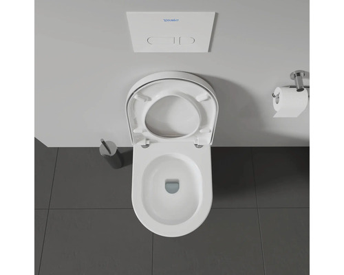 Photo de toilettes avec abattant ouvert, chasse d'eau, papier toilette et brosse de toilette.