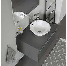 Salle de bain moderne avec vasque à poser, robinetterie, miroir et porte-serviettes.