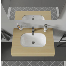 Vue de dessus d'un meuble de salle de bains avec lavabo, robinet, distributeur de savon, gobelet, miroir et tapis