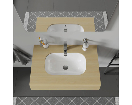 Vue de dessus d'un meuble de salle de bains avec lavabo, robinet, distributeur de savon, gobelet, miroir et tapis