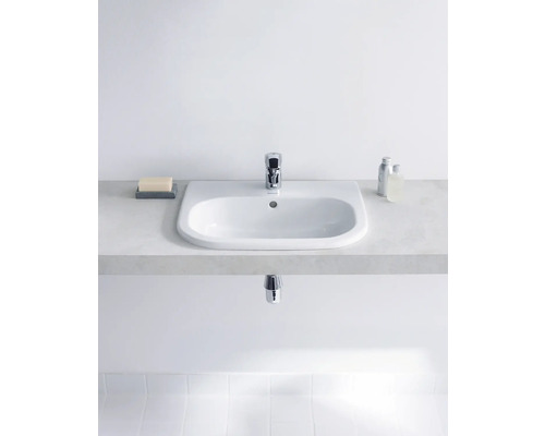 Lavabo en céramique avec robinet sur un meuble sous-lavabo dans la salle de bain.