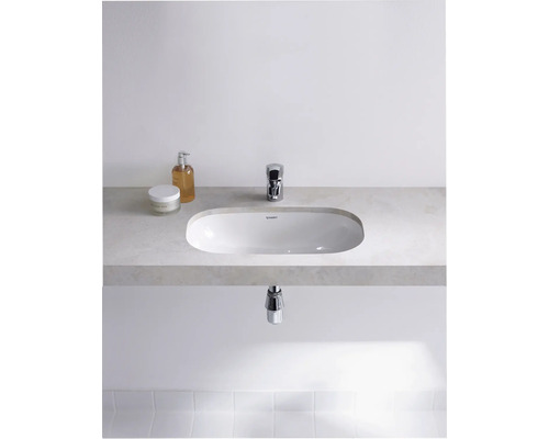 Salle de bains moderne avec lavabo à poser, robinet et produits de soin sur une étagère.