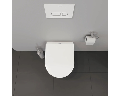 Salle de bains avec toilettes, plaque de commande, brosse de toilette et porte-papier hygiénique