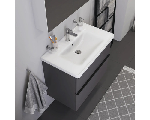 Waschtisch mit Unterschrank, Armatur, Seifenspender, Handtuch und Teppich in einem Badezimmer