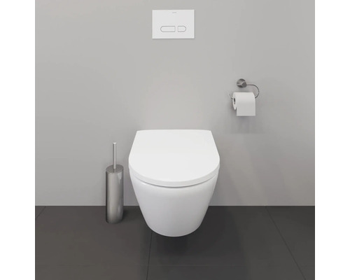 WC suspendu à fond creux avec plaque de commande, support de papier toilette et ensemble de brosse WC dans une salle de bains.
